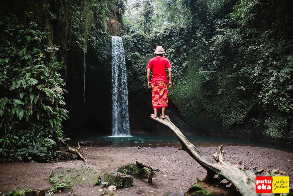 Air Terjun Tibumana dengan Putu Eka Jalan Jalan sedang berdiri diatas pohon kering