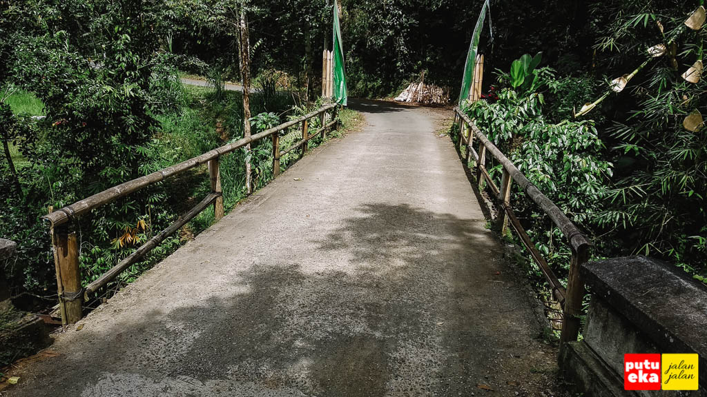 Jembatan dengan pagar bambu didekat air terjun