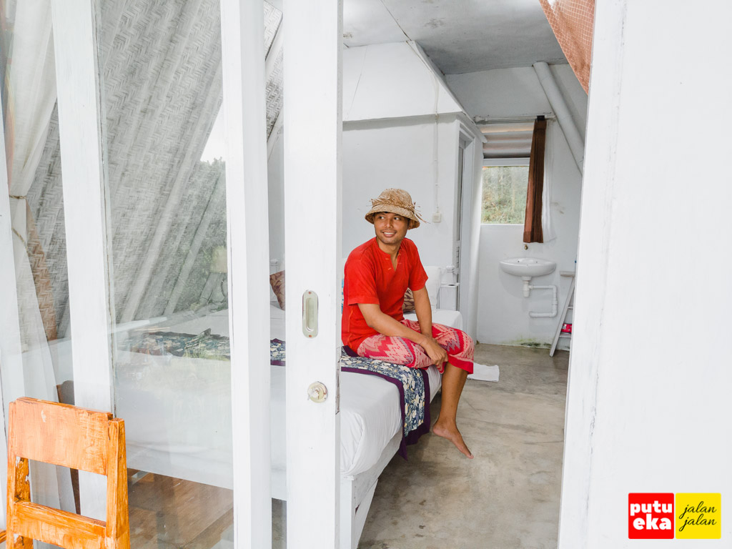 Putu Eka Jalan Jalan sedang duduk di dalam kamar Padi Bali Cottages